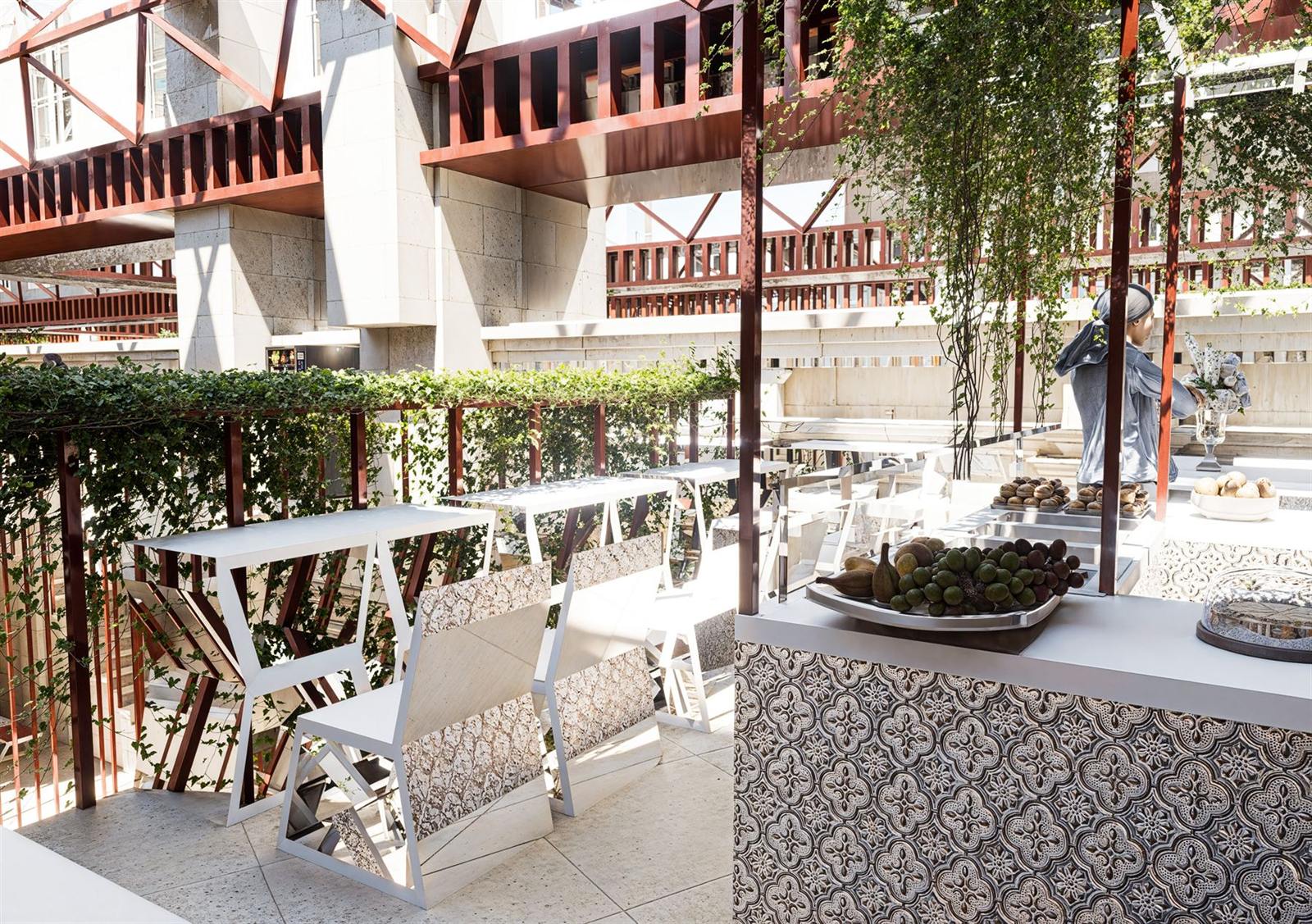 Espace restauration de la verrière, mobilier blanc, végétation et dallage à motifs